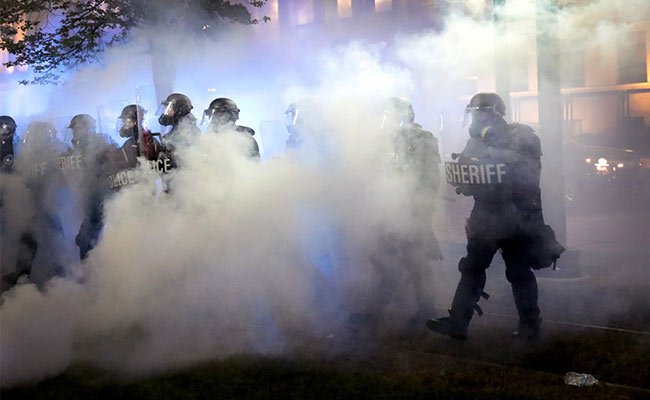 As tear gas fills the air, police try to push back demonstrators near the Kenosha County Courthouse